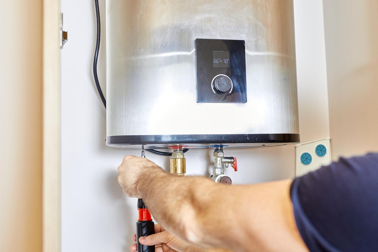 Plumber tightening a nut in water heater system