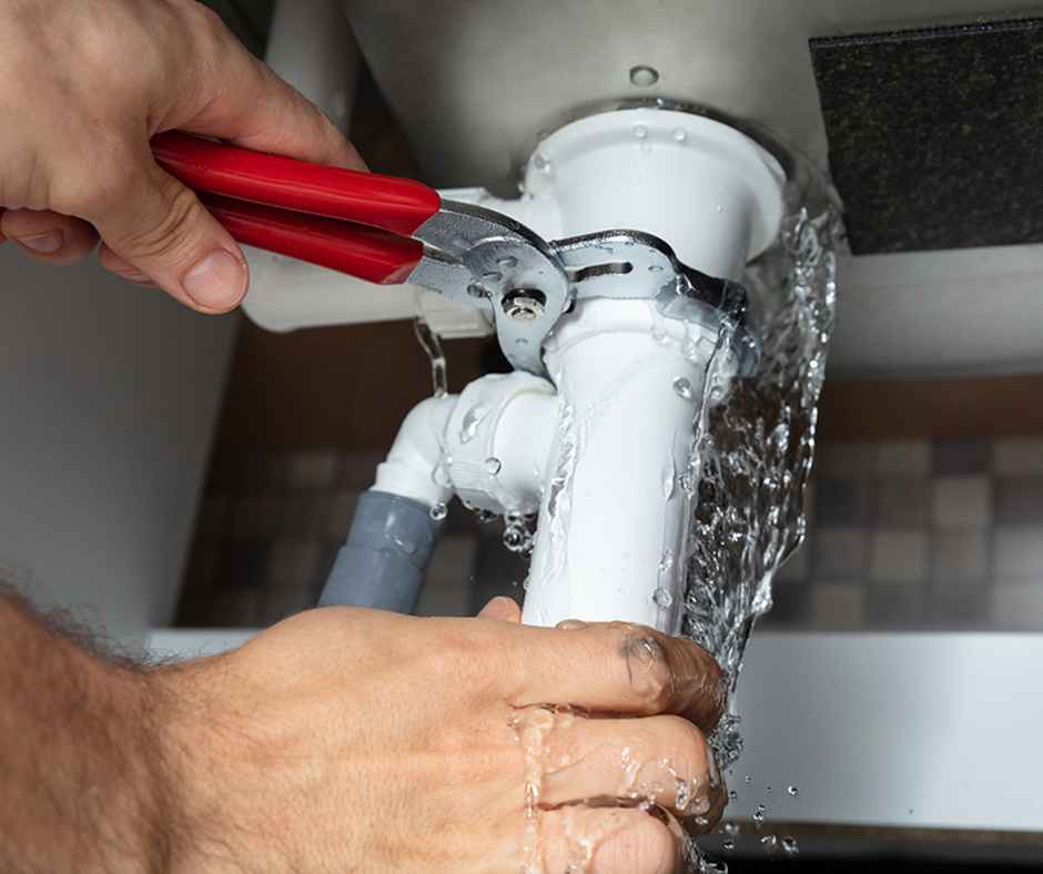 Leaking pipe being fixed by plumber